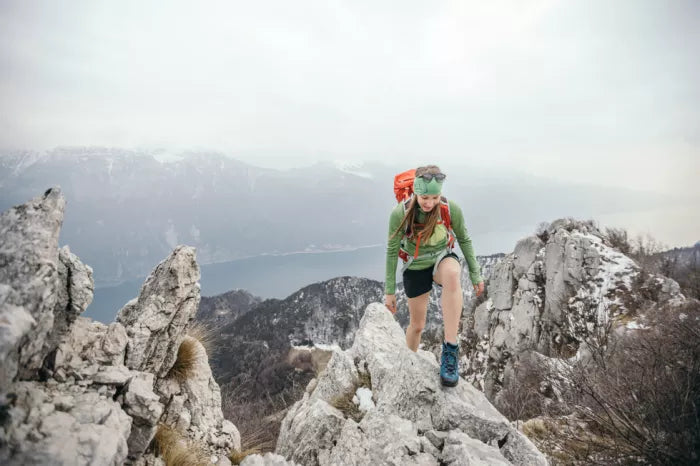 A woman climbing a mountain on a cloudy day with LOWA footwear