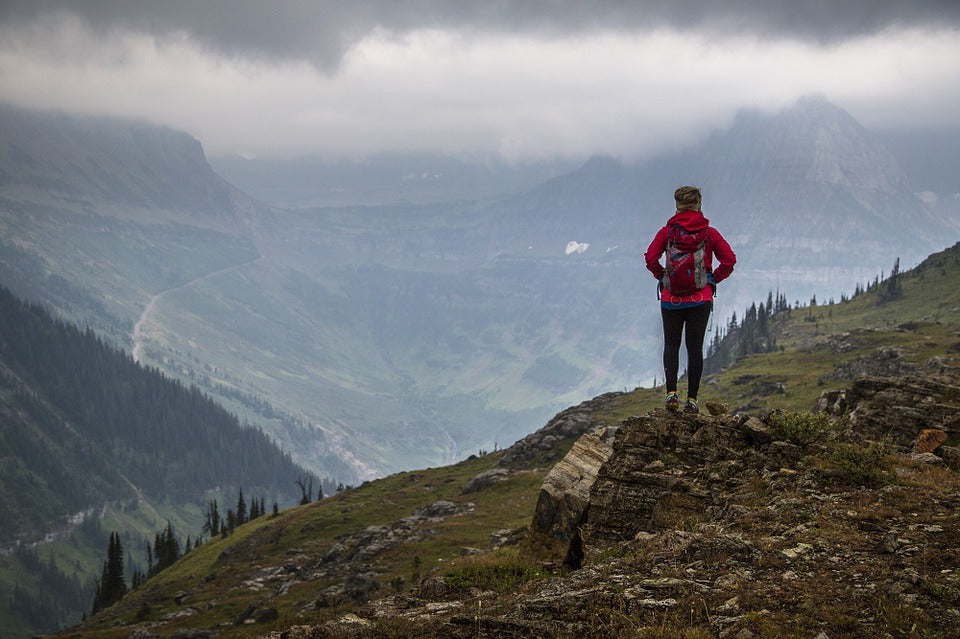 A hiker on a mountain overlooking the foggy landscape