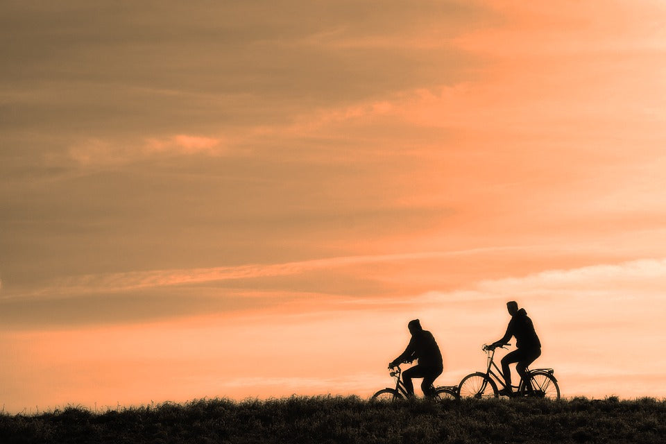 A silhouette of people cycling on a hill