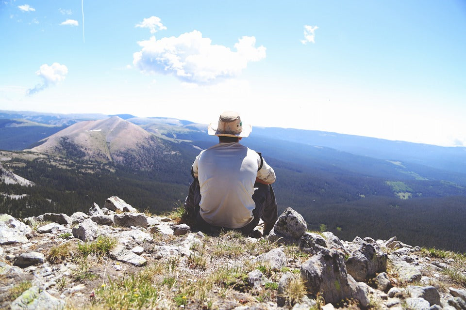 A man sat down overlooking a mountain range