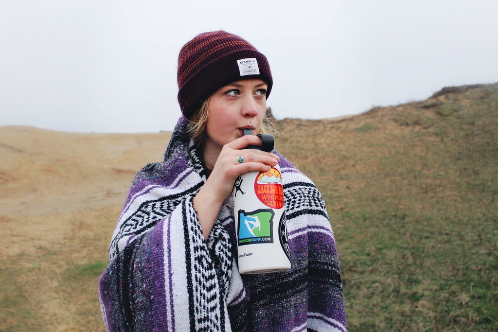 woman drinking from a water bottle on a hike