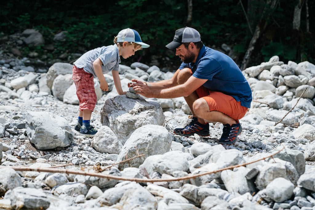 Father and son building a tower of stones in LOWA footwear