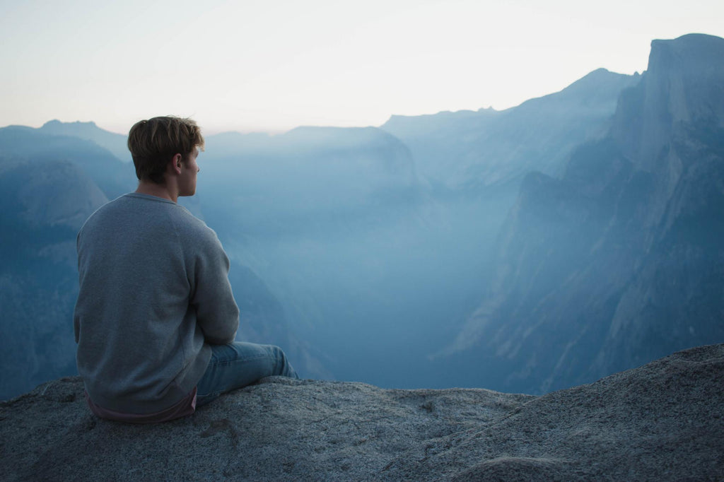 A boy looking over misty mountain peaks. 