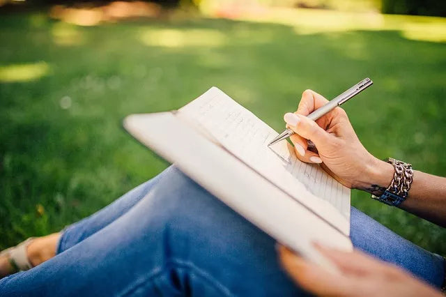 A girl outside writing in her journal