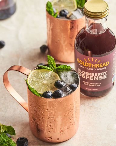 Goldthread Plant-Based Tonics Elderberry Mule in a copper mug garnished with mint, lemon, and blueberries