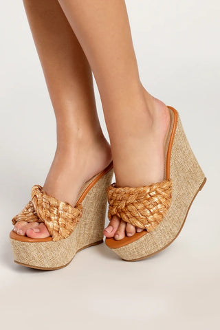 Una modelo de pie lleva sandalias de cuña con plataforma de rafia color canela Chantiele de lulus.com