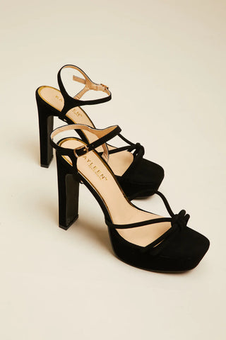 una modelo con sandalias negras de tacón con plataforma KAYLEEN Reach for the Sky de York & Dante, una boutique en línea para mujeres.