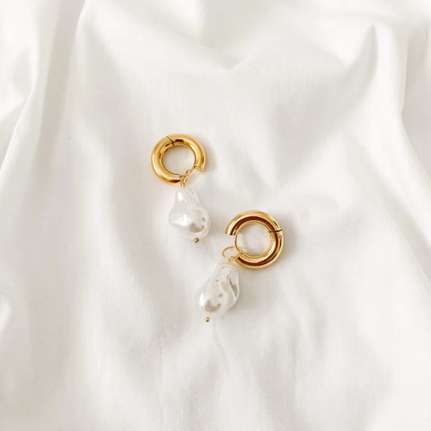 Une photographie de boucles d'oreilles Nuria en fausse perle d'or sur fond blanc