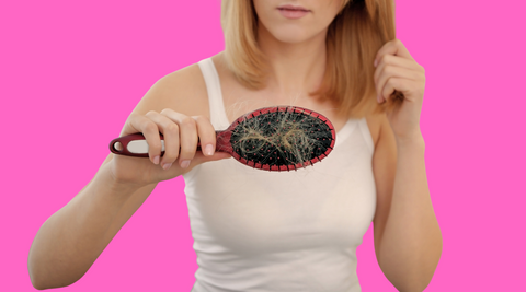 Woman with alopecia holding a hair brush with tangled blond hair