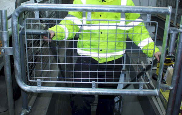 person walking upstairs to enter through safety gate wearing a high visibility jacket