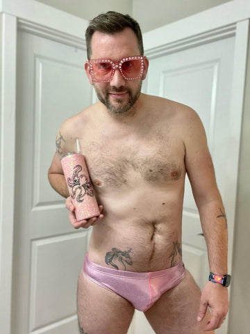 Keith in metallic pink "The Kraken" wearing rhinestone sunglasses and holding a TSM Swimwear metallic pink cup