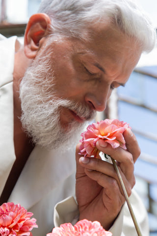 Man With White Hair And Beard Smelling A Rose