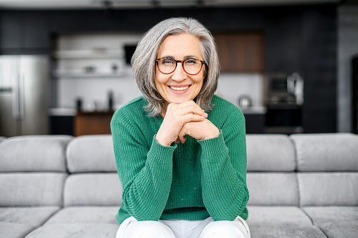 Woman With Wavy Gray Hair Sitting On Couch Gray Hair Styling Tips