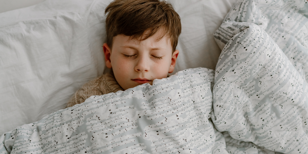 Boy sleeping under Nest Designs blanket