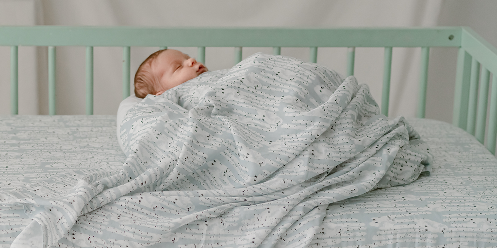 Baby sleeping on Nest Designs crib sheet