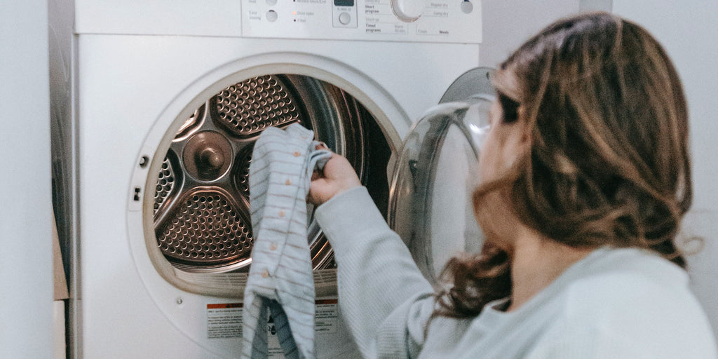 Hand placing baby clothes in washer