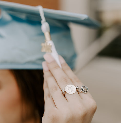 Person holding a graduation cap tassel wearing a silver fidget ring