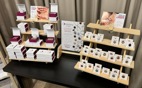 Display of CONQUERing products: features boxes holding jewelry, bases, elements, and signage.