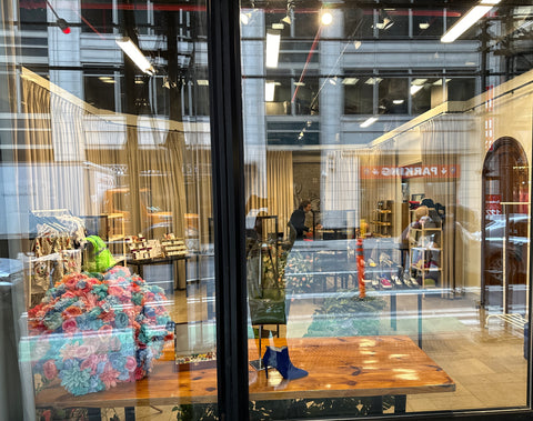 Looking through a storefront window with tables set up with clothing and jewelry for sale