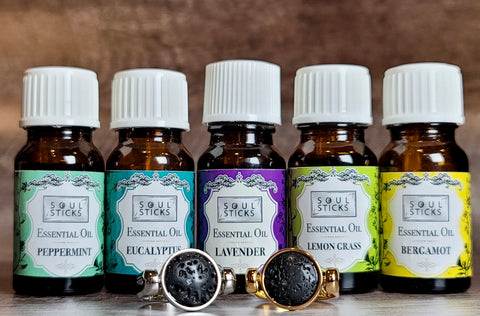 Five Essential Oils in colorful bottles lined up behind silver and gold lava stone fidget rings