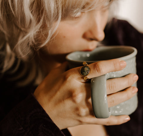 Person drinking a cup of coffee wearing a Rainforest Jasper Fidget Ring