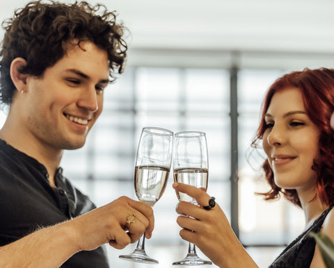 Two people clinking glasses, wearing black and gold fidget rings