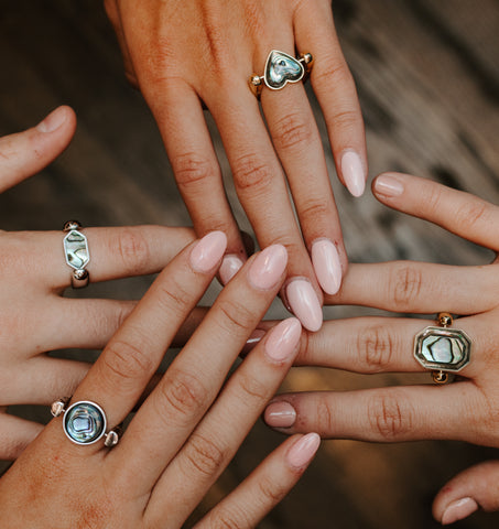 Four People putting their hands together, all are wearing Abalone Shell Fidget Ring