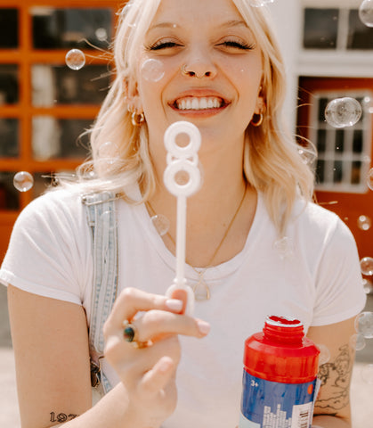 Person blowing bubbles and smiling wearing a holographic fidget ring