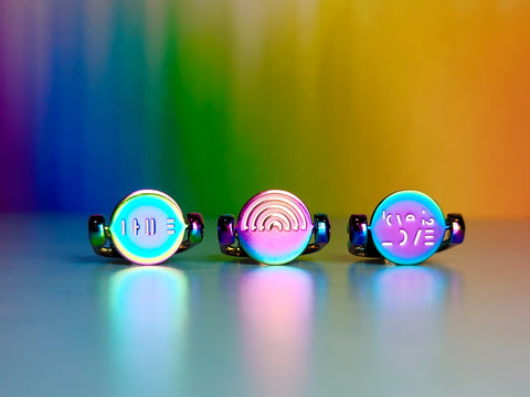 three pride rings in rainbow colors on a rainbow background