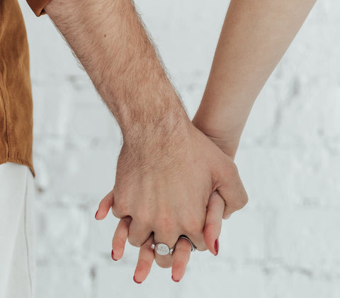 Two people holding hands, one wears a silver fidget ring