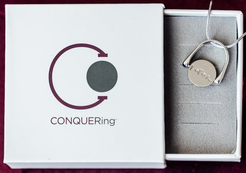 Silver Fidget Necklace that says Believe in a CONQUERing branded box