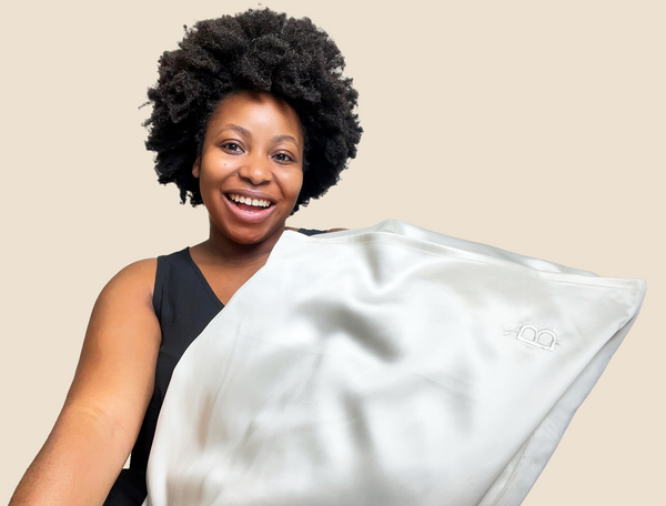 woman with black coily 4c type hair holding a Bouclème silk pillowcase