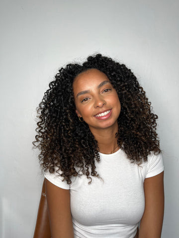 Woman facing the camera in a white t-shirt with black, coily hair