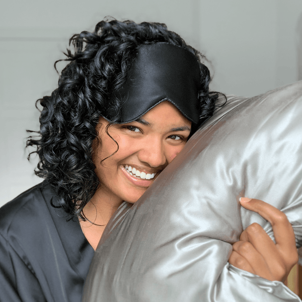 Woman with black curly hair and an eye mask leaning on Boucleme's slik pillowcase