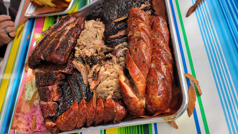 Delicious barbecue platter from ZZQ Texas Craft Barbeque in Richmond, featuring a mouth-watering assortment of ribs, pulled pork, and sausages, showcasing their renowned slow-cooked meats and vibrant flavors.