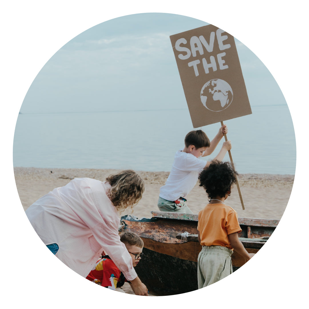 Children on the ocean holding a 'save the earth' sign made of cardboard