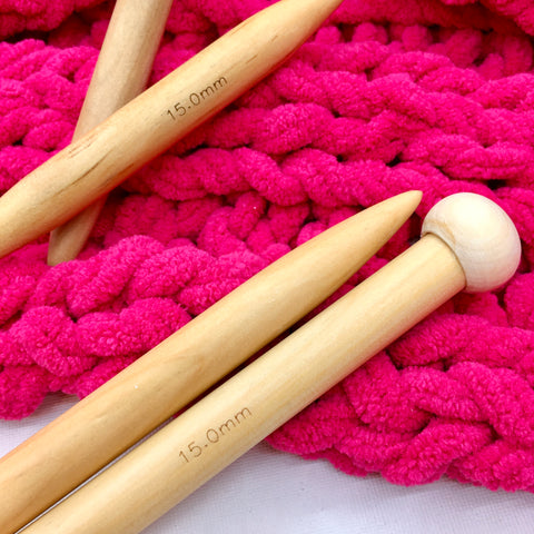 15mm beech wood knitting needle on top of pink knitted fabric