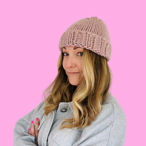 Girl with blonde hair wearing a knitted peach merino wool beanie hat