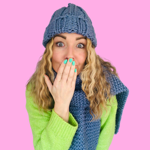Girl wearing a blue knitted scarf and hat with a lime green jumper on