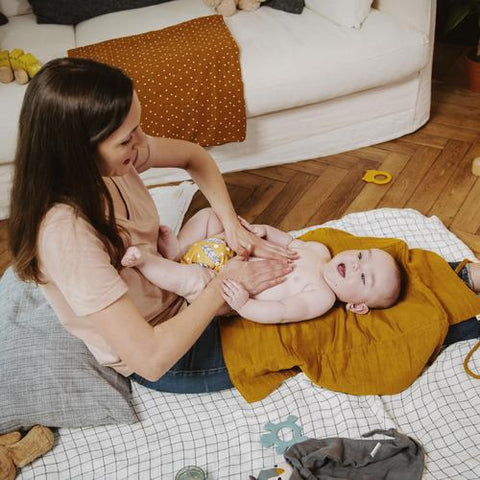 Una madre está dando un masaje a su bebé para aliviar su estreñimiento