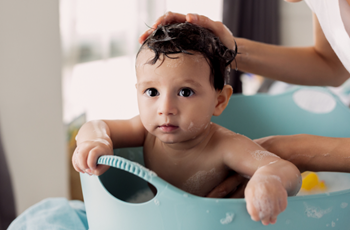 Un bebé disfruta de su baño con un reductor de bañera para ahorrar agua, al reducir la cantidad necesaria