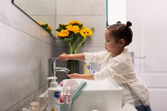 Una niña cierra el grifo al lavarse los dientes y la cara para ahorrar agua