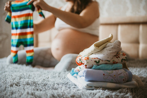 Una mujer embarazada elige la ropa de su futuro recién nacido