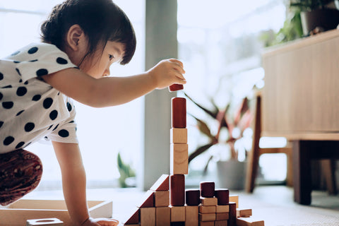 Una niña está jugando con cubos de madera