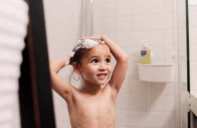 Una niña se enjabona el cabello en la ducha, reduce el consumo de agua en comparación con una bañera