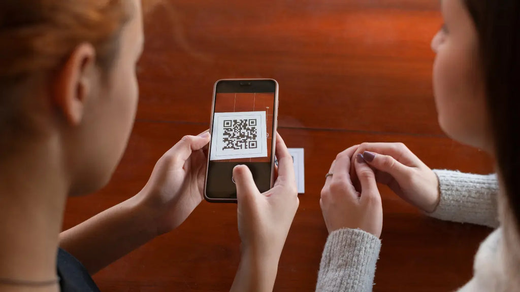 Une femme scannant à l'aide de son portable un QR Code sur une table.