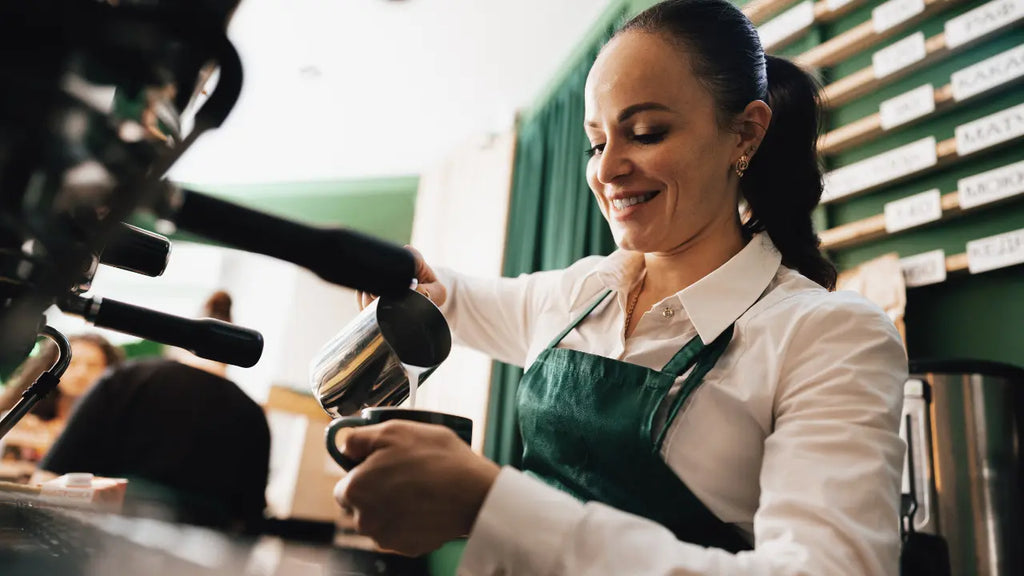 Une barrista chez Starbucks qui est en train de mettre du lait dans un café