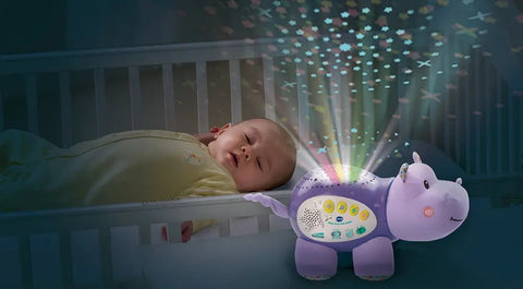 Un bébé paisiblement endormi dans son petit lit, accompagné d'une veilleuse de marque Vtech en forme d'hippopotame violet qui diffuse des étoiles et de la musique, illustrant l'efficacité des veilleuses musicales et projectrices pour aider les bébés à s'endormir.