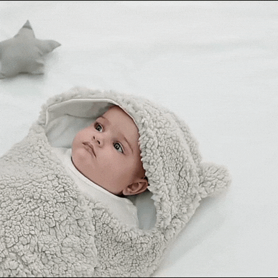 Gif animé montrant un bébé endormi confortablement dans un nid d'ange doux de couleur gris - la sérénité pour les siestes de bébé.