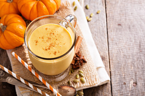 pumpkin smoothie in a glass surrounded by pumpkins
